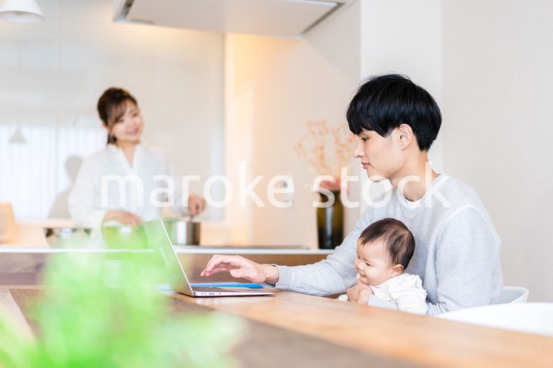 赤ちゃんと一緒にパソコンを使うパパ