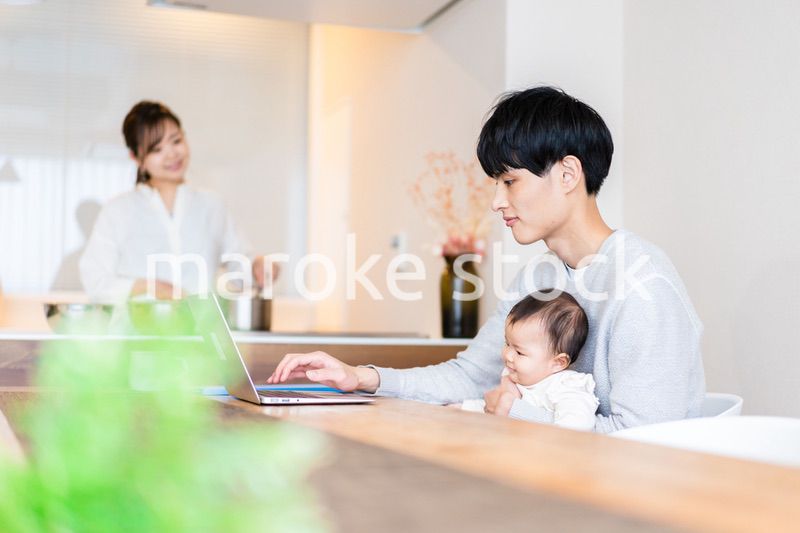 赤ちゃんと一緒にパソコンを使うパパ