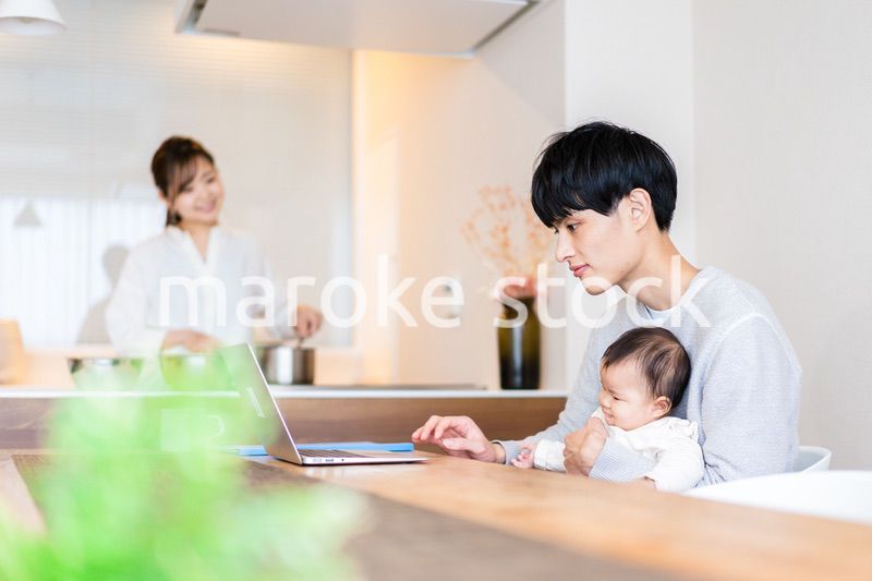 赤ちゃんと一緒にパソコンを使うパパ