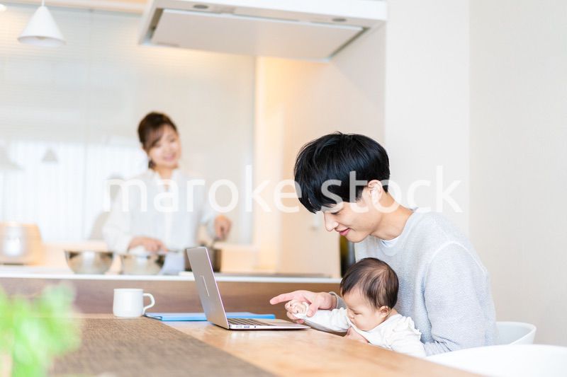 赤ちゃんと一緒にパソコンを使うパパ