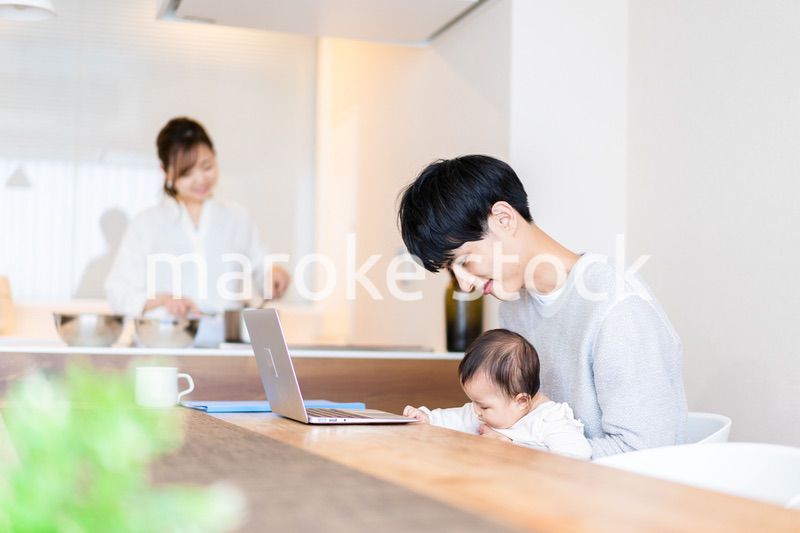 赤ちゃんと一緒にパソコンを使うパパ