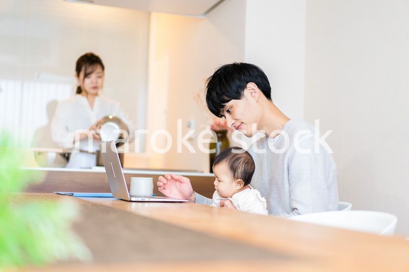 赤ちゃんと一緒にパソコンを使うパパ