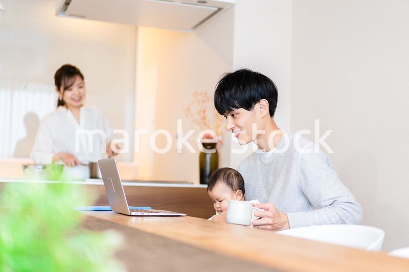 赤ちゃんと一緒にパソコンを使うパパ