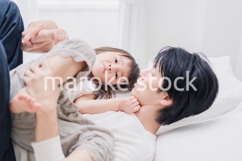 パパと一緒にベッドで遊ぶ小さな女の子