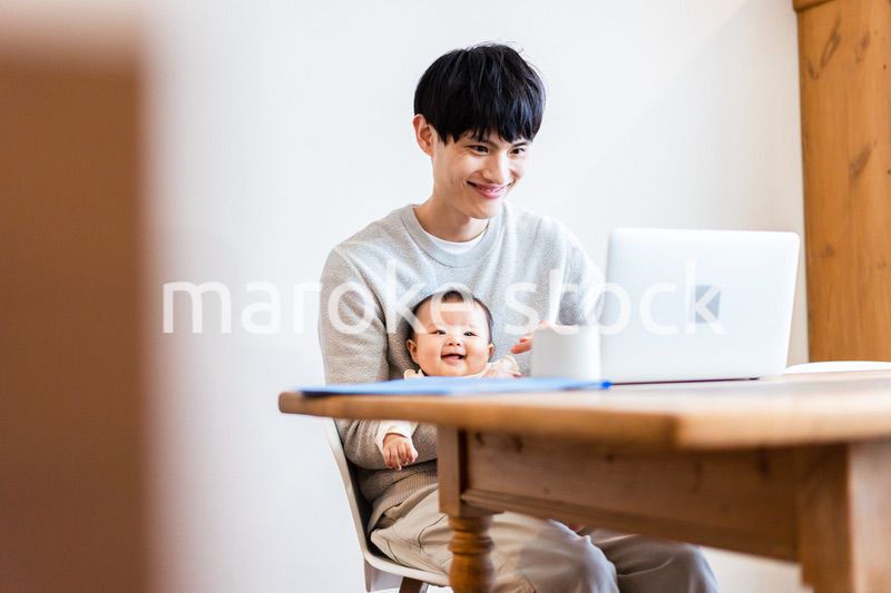 赤ちゃんをお世話しながら在宅勤務をするパパ