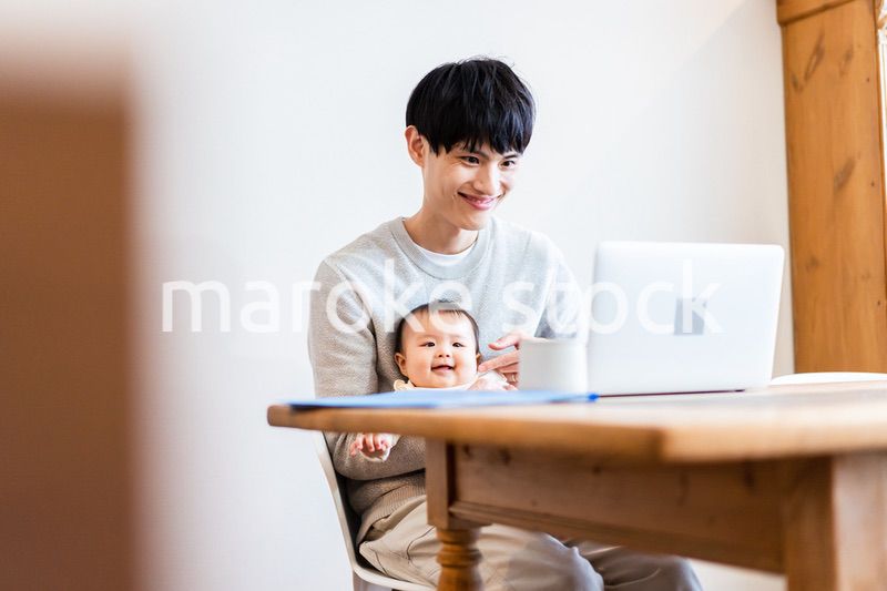 赤ちゃんをお世話しながら在宅勤務をするパパ