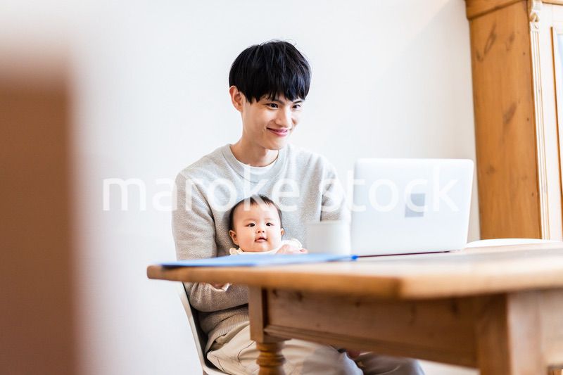 赤ちゃんをお世話しながら在宅勤務をするパパ