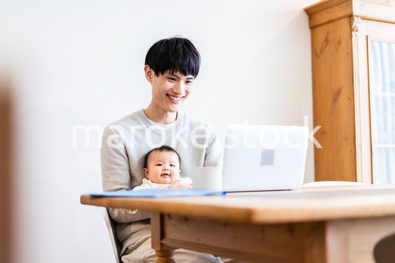 赤ちゃんをお世話しながら在宅勤務をするパパ