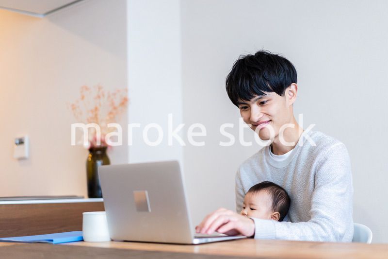 赤ちゃんをお世話しながら在宅勤務をするパパ