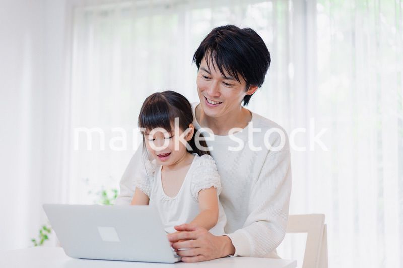 お父さんと一緒にパソコンを使う小さな女の子