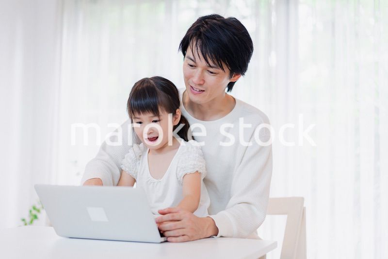 お父さんと一緒にパソコンを使う小さな女の子