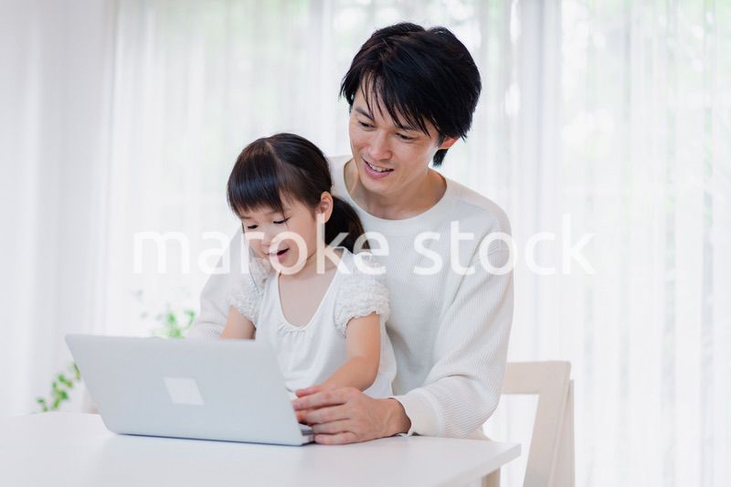 お父さんと一緒にパソコンを使う小さな女の子
