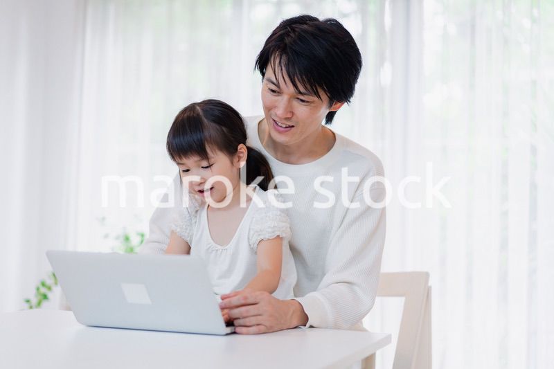 お父さんと一緒にパソコンを使う小さな女の子