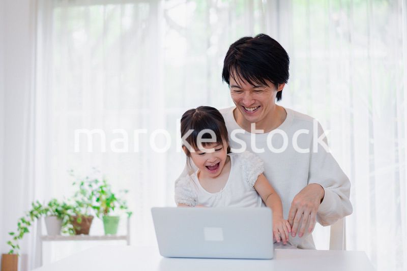 お父さんと一緒にパソコンを使う小さな女の子