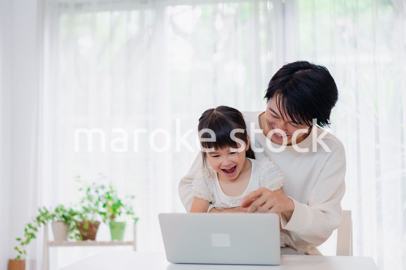 お父さんと一緒にパソコンを使う小さな女の子