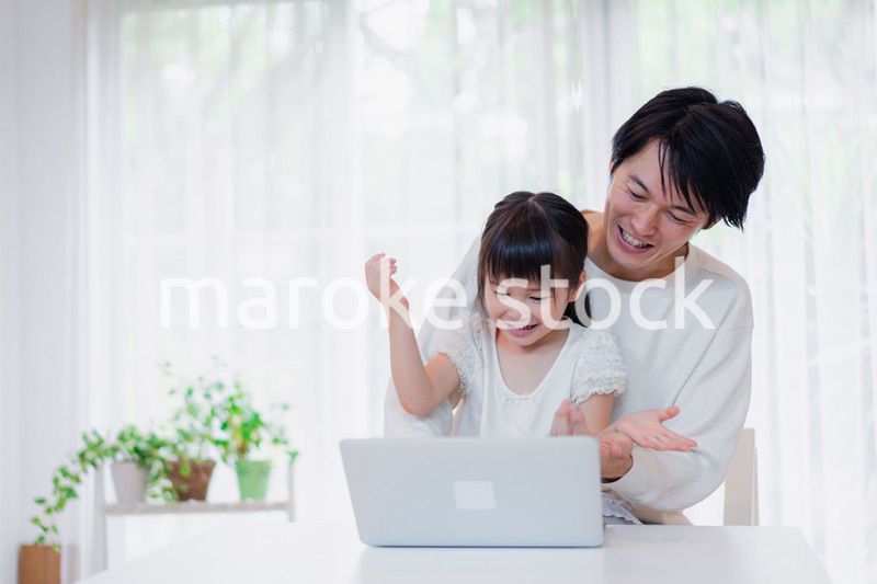 お父さんと一緒にパソコンを使う小さな女の子