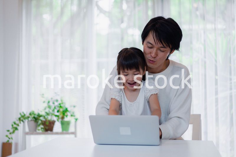 お父さんと一緒にパソコンを使う小さな女の子