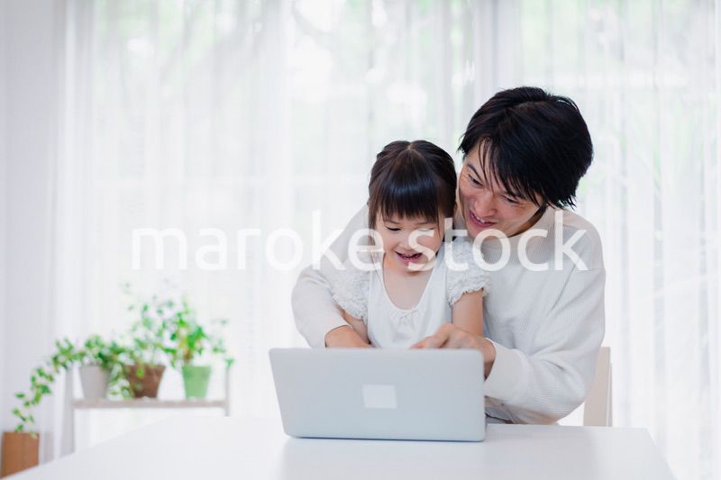 お父さんと一緒にパソコンを使う小さな女の子
