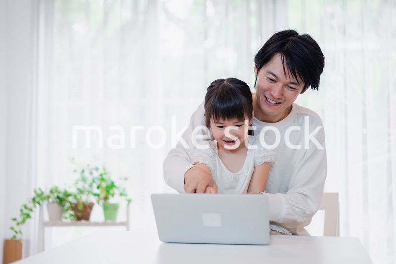 お父さんと一緒にパソコンを使う小さな女の子