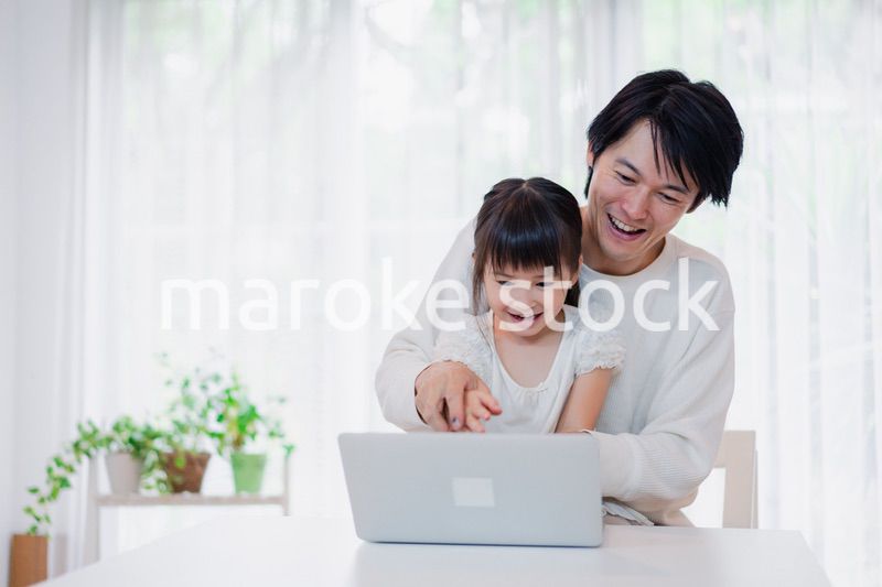 お父さんと一緒にパソコンを使う小さな女の子