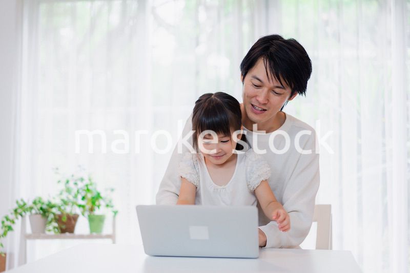 お父さんと一緒にパソコンを使う小さな女の子