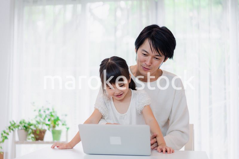 お父さんと一緒にパソコンを使う小さな女の子