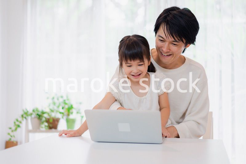 お父さんと一緒にパソコンを使う小さな女の子