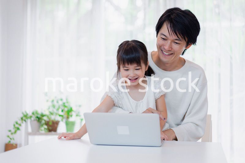 お父さんと一緒にパソコンを使う小さな女の子