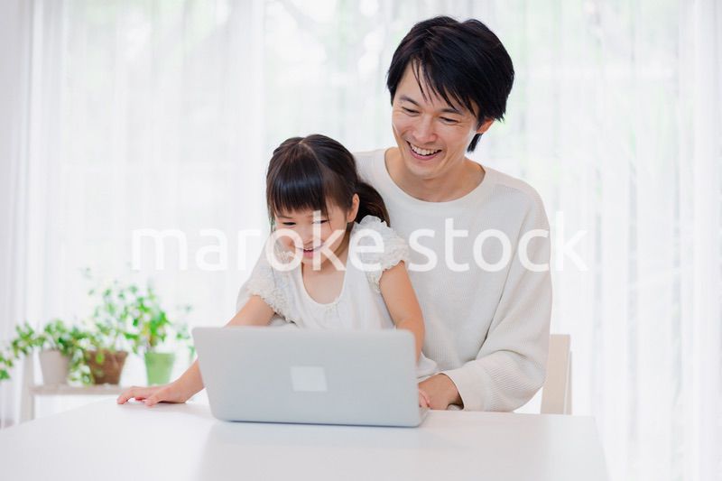 お父さんと一緒にパソコンを使う小さな女の子