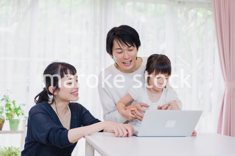 子供と一緒にパソコンで遊ぶ家族