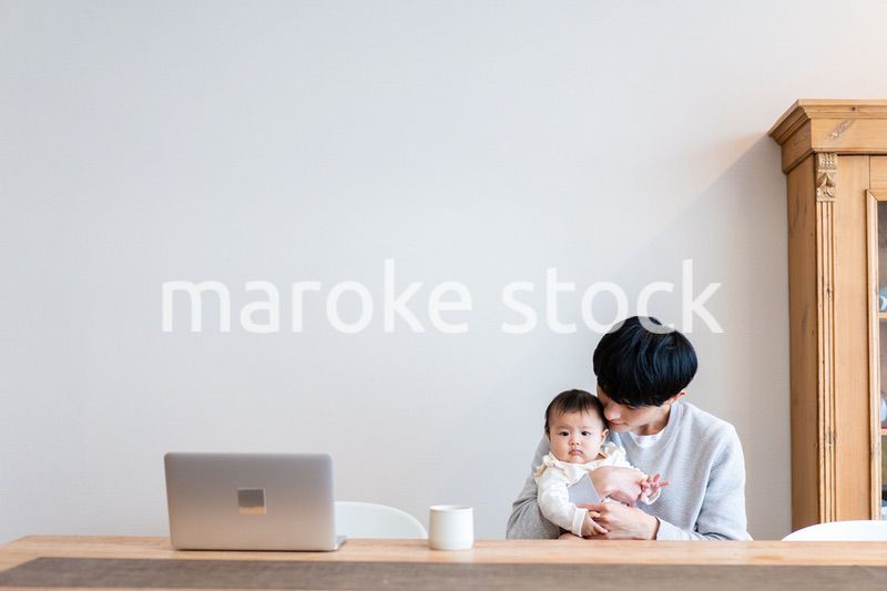 赤ちゃんをお世話しながら在宅勤務をするパパ