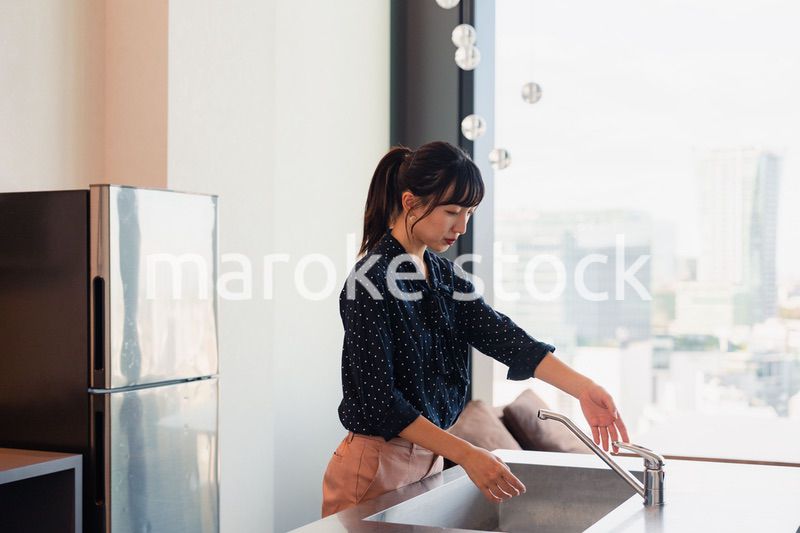 タワーマンションのモデルルームでキッチンの確認をする女性