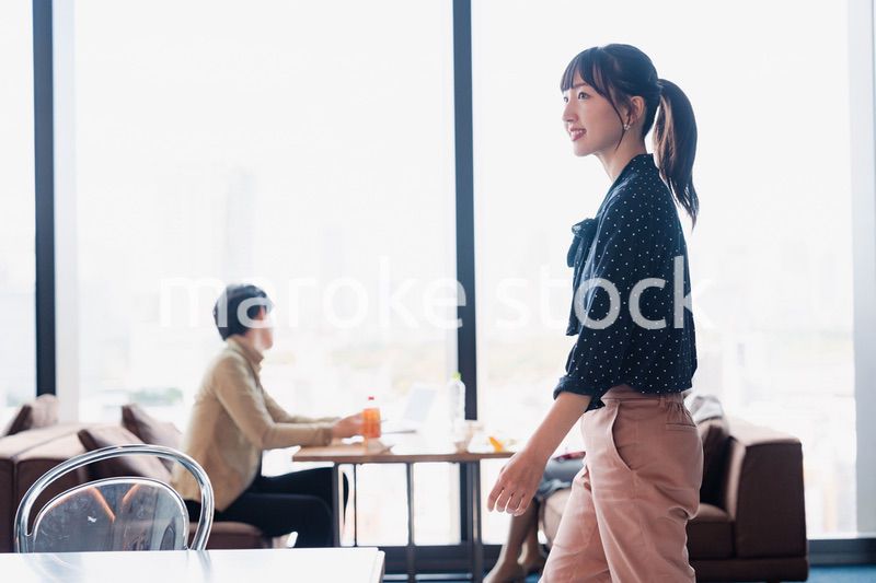 モダンな雰囲気のオフィスのカフェテリアを歩くキャリアウーマン