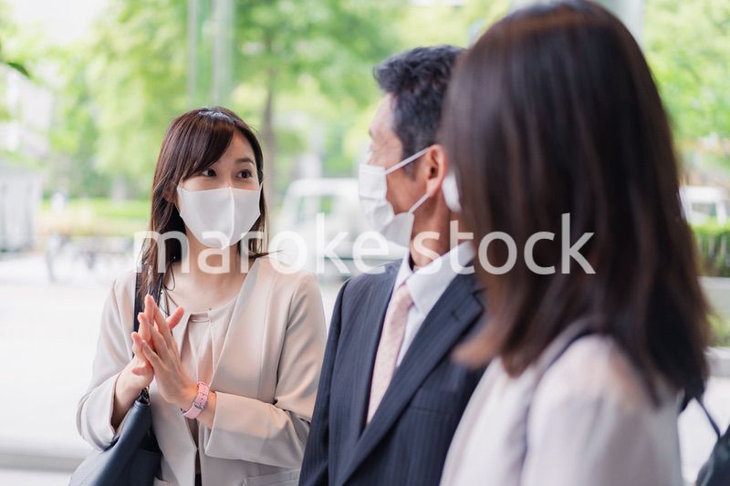 マスクをしてオフィスで立ち話をするビジネスパーソン