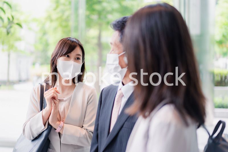 マスクをしてオフィスで立ち話をするビジネスパーソン