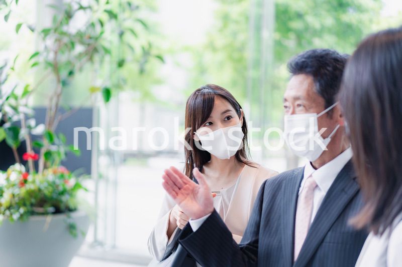 マスクをしてオフィスで立ち話をするビジネスパーソン