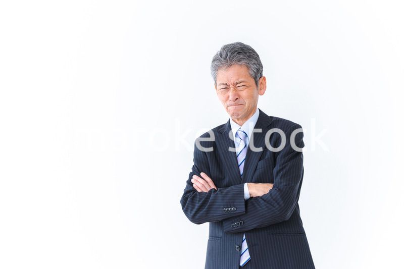 腕を組み厳しい表情をするビジネスマン