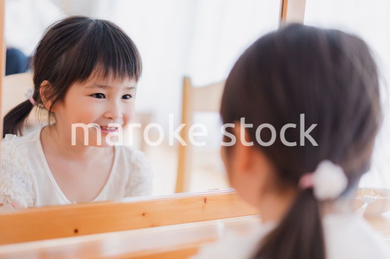 鏡で自分の顔を見る女の子