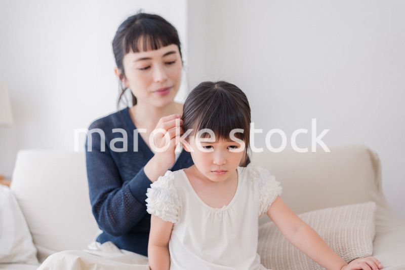 娘の髪を結ぶお母さん