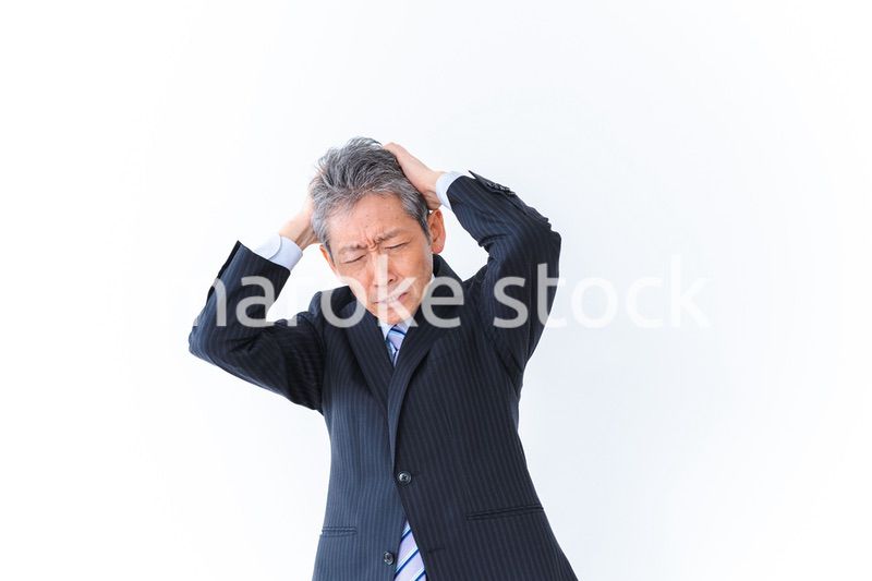頭を抱える中年のビジネスマン