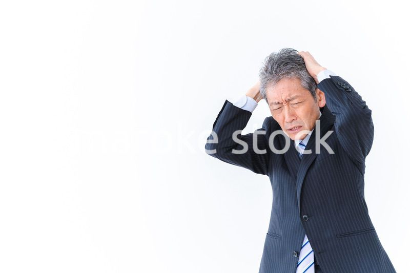 頭を抱える中年のビジネスマン