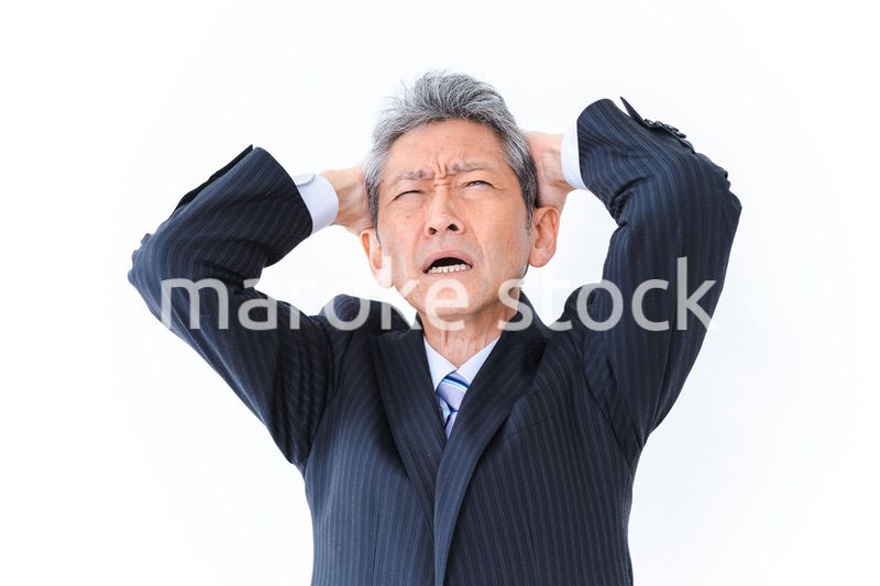 頭を抱える中年のビジネスマン
