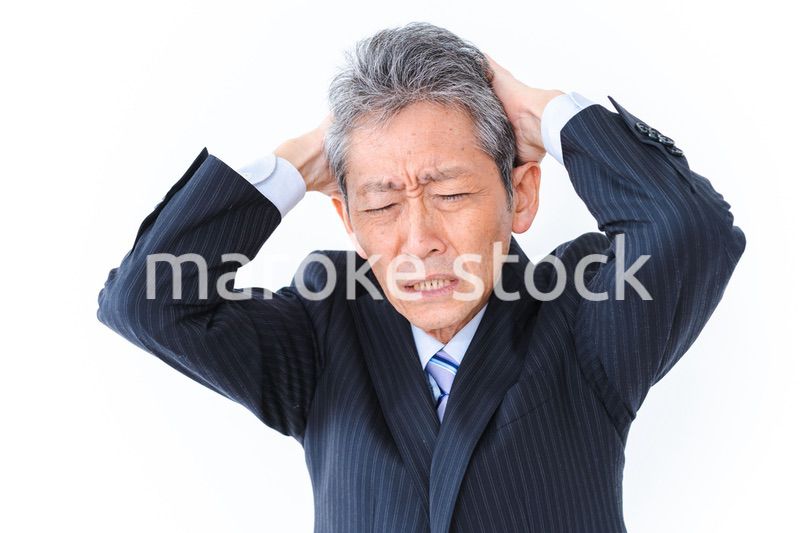 頭を抱える中年のビジネスマン