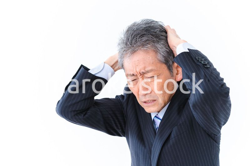頭を抱える中年のビジネスマン