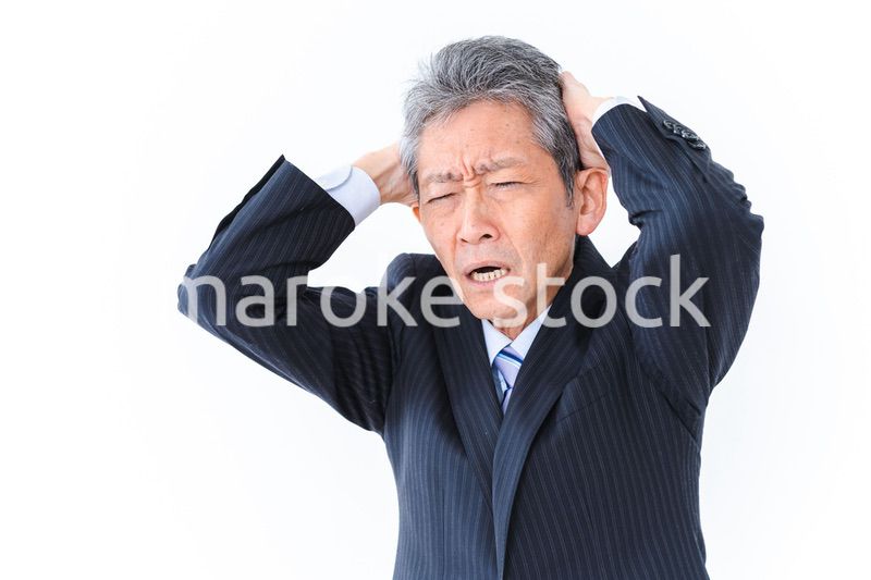 頭を抱える中年のビジネスマン