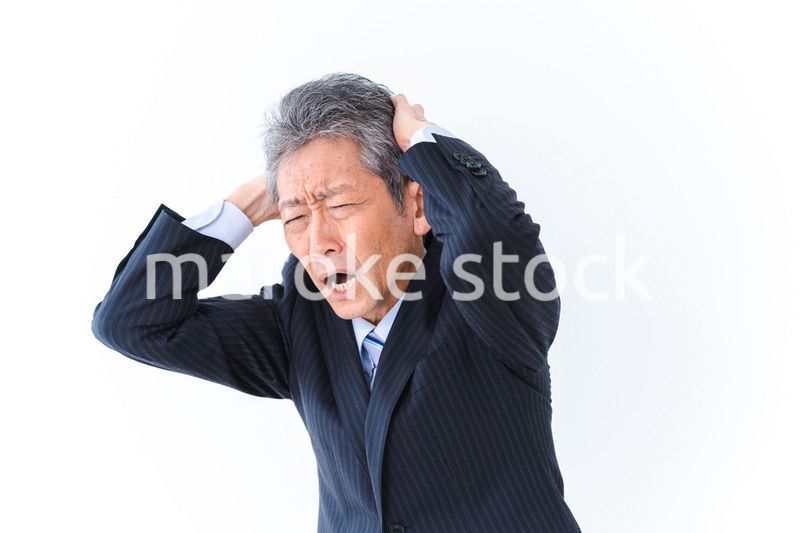 頭を抱える中年のビジネスマン