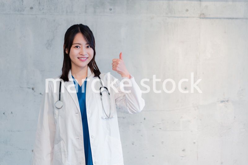笑顔でグッドサインをする女性ドクター