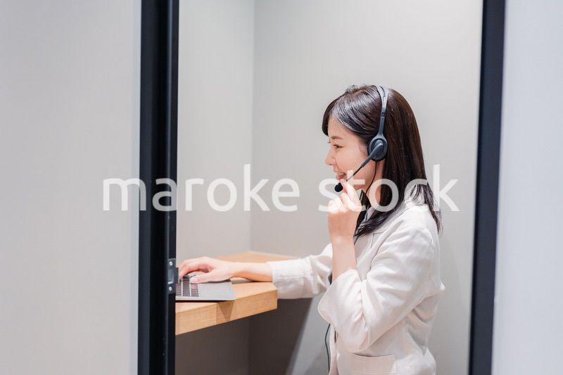 シェアオフィスの個室ブースでリモート会議をする女性