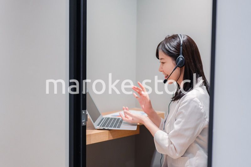 シェアオフィスの個室ブースでリモート会議をする女性