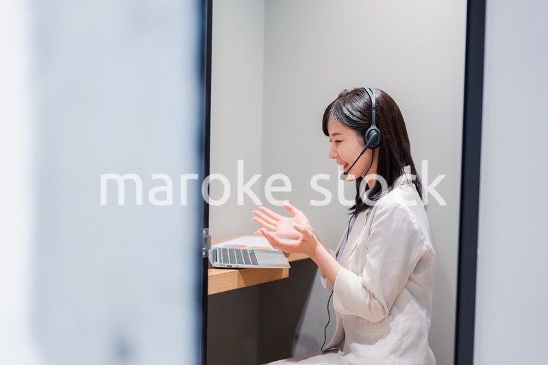 シェアオフィスの個室ブースでリモート会議をする女性
